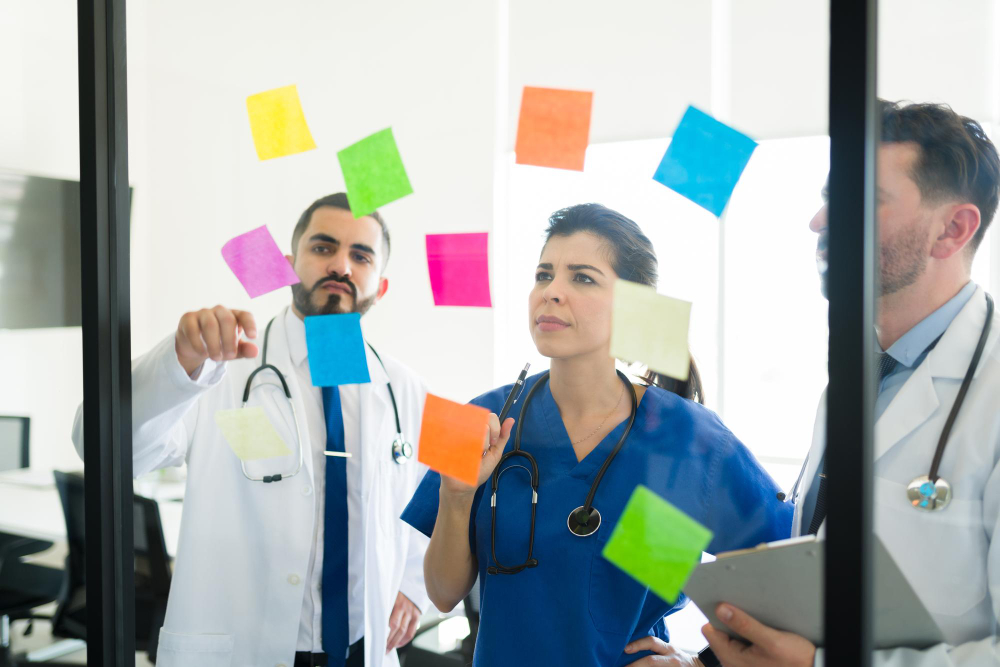 Doctors discussing potential ideas and examples of patient experience goals while brainstorming with sticky notes.