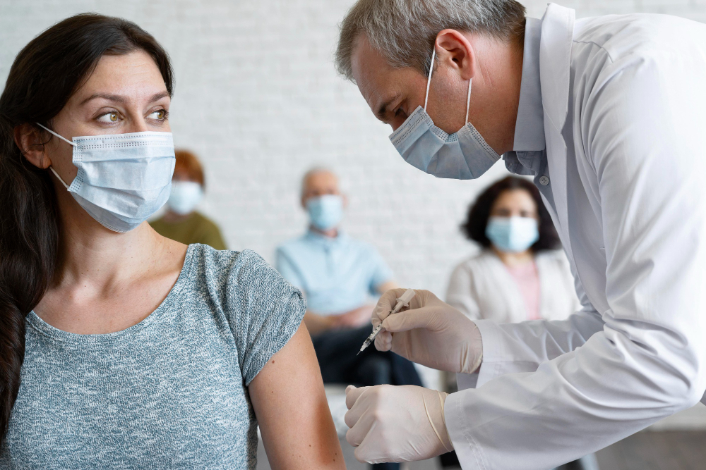 A healthcare worker administers a vaccine to a masked woman during an employee vaccination tracking event.