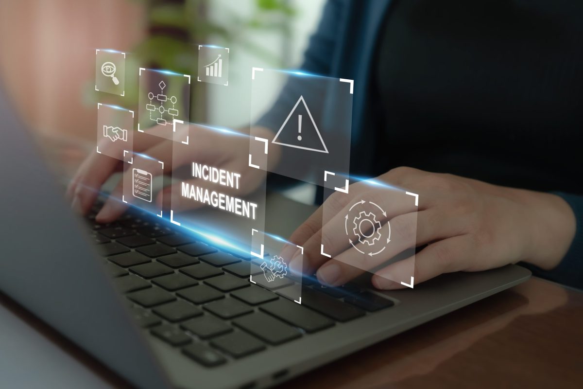 A person types on a laptop keyboard with a series of floating icons related to the top incident management software healthcare professionals trust displayed above.